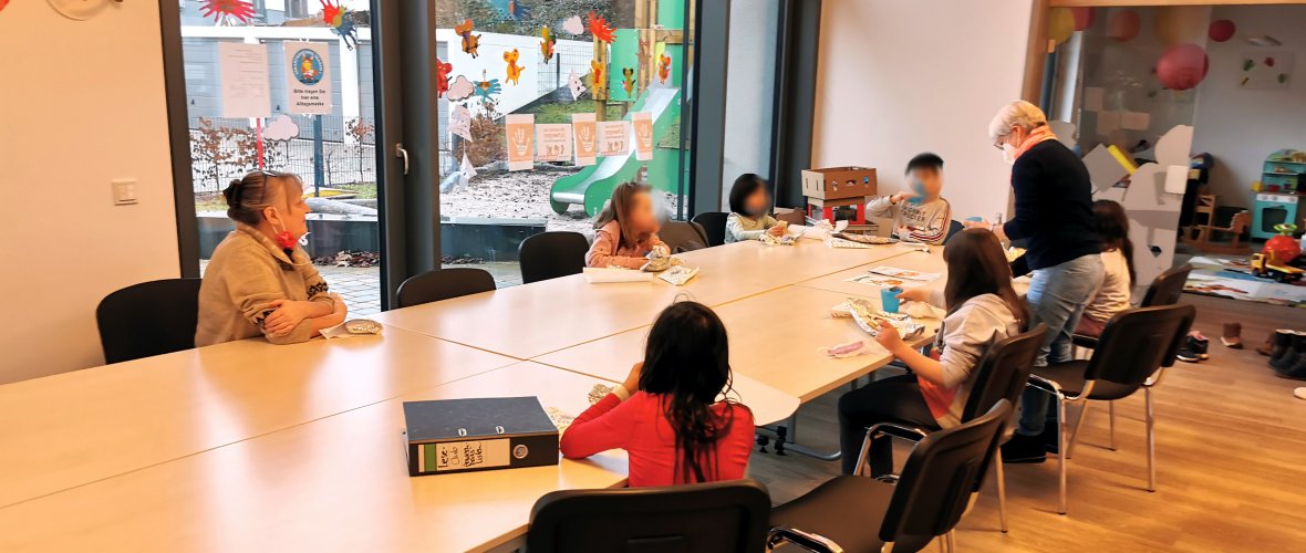 Kinder und Mitarbeiterinnen des Leseclubs sitzen am Tisch und essen Crêpes