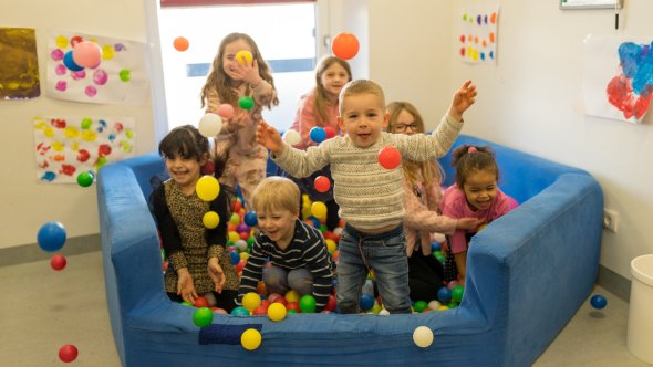 Kinder werfen Bälle aus einem Bällebad