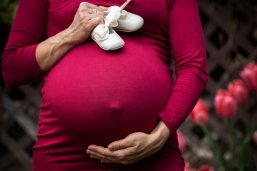 Schwangere Frau im roten Kleid, Fokus auf Bauch