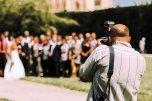 Blick über die Schulter des Hochzeitsfotografen, im Hintergrund verschwommen die Hochzeitsgesellschaft