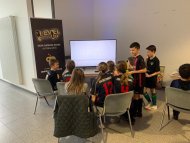 Kinderfußballmannschaft sitzt zusammen vor dem Fernseher im Level Up Pirmasens 