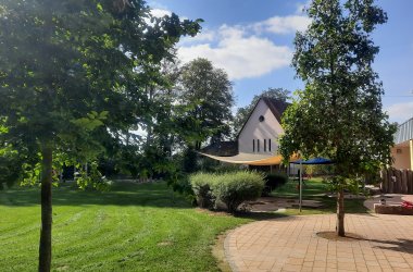 Kitagebäude, Garten und Bäume und ein kleiner Spielplatz