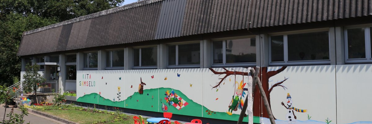 KiTa "Samselo" Sommerwald Abgebildet ist das Gebäude der Kita mit Wandgemälde (verschiedene Jahreszeitenmotive vom Samselo)