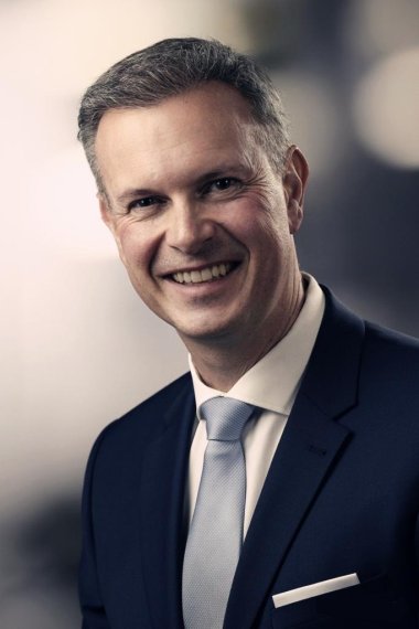 Portraitfoto von Bürgermeister Michael Maas vor neutralem Hintergrund im Anzug