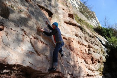 Bouldern am Felsmassiv Ein Mann klettern mit Helm an einem imposanten Buntsandsteinmassiv